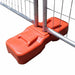 Orange plastic fence base for securing temporary barriers, durable and weather-resistant.