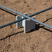 Gray rebar support holder on dirt with two steel rebars crossing for concrete reinforcement.